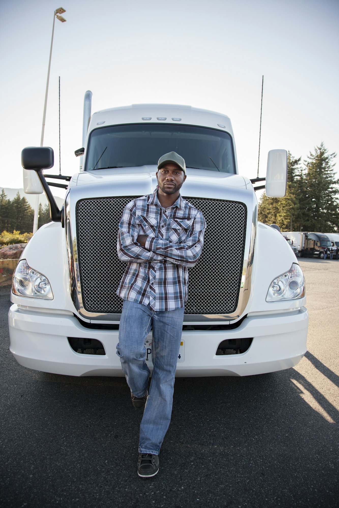 Black man truck driver near his truck parked in a parking lot at a truck stop